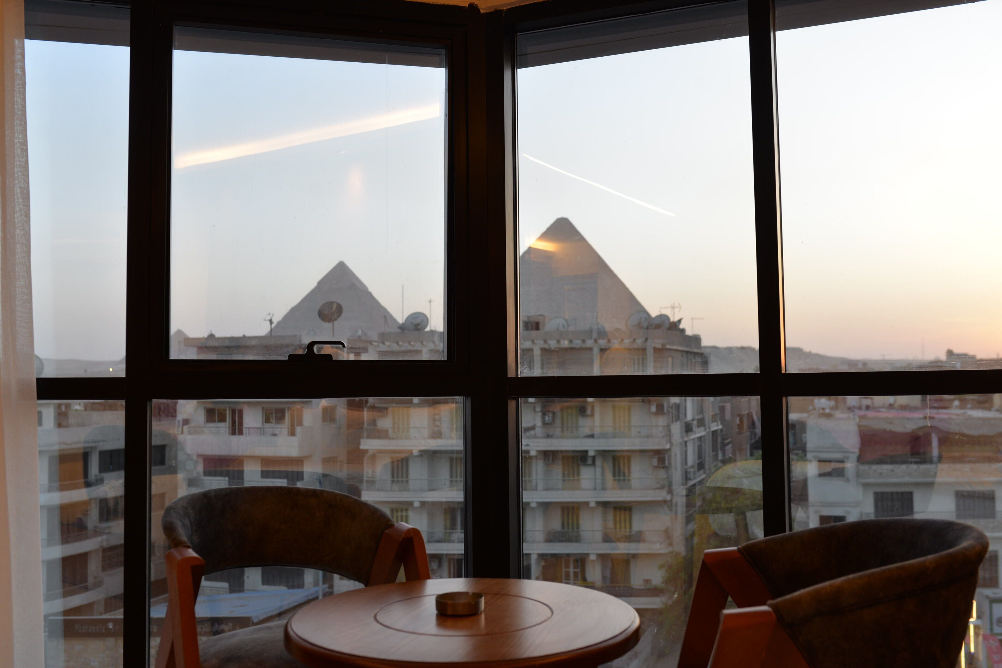 A room with a view of pyramids through large windows.