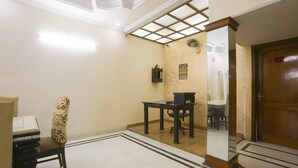 Een kamer met een houten deur, een tafel met een stoel, een spiegel en een gestreept fauteuil.