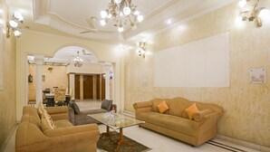 Een ruime woonkamer met een beige bank, een glazen salontafel en een kroonluchter.