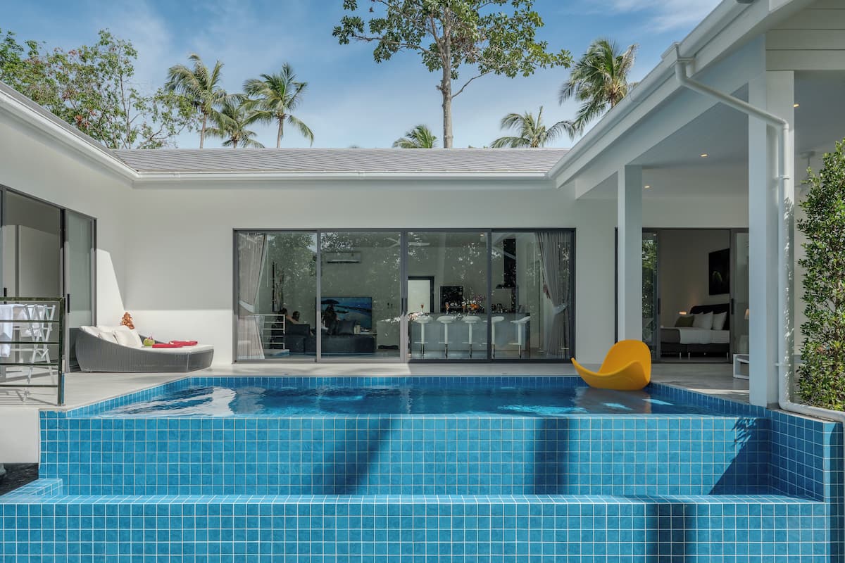 A modern house with a swimming pool, large windows, and a patio area.