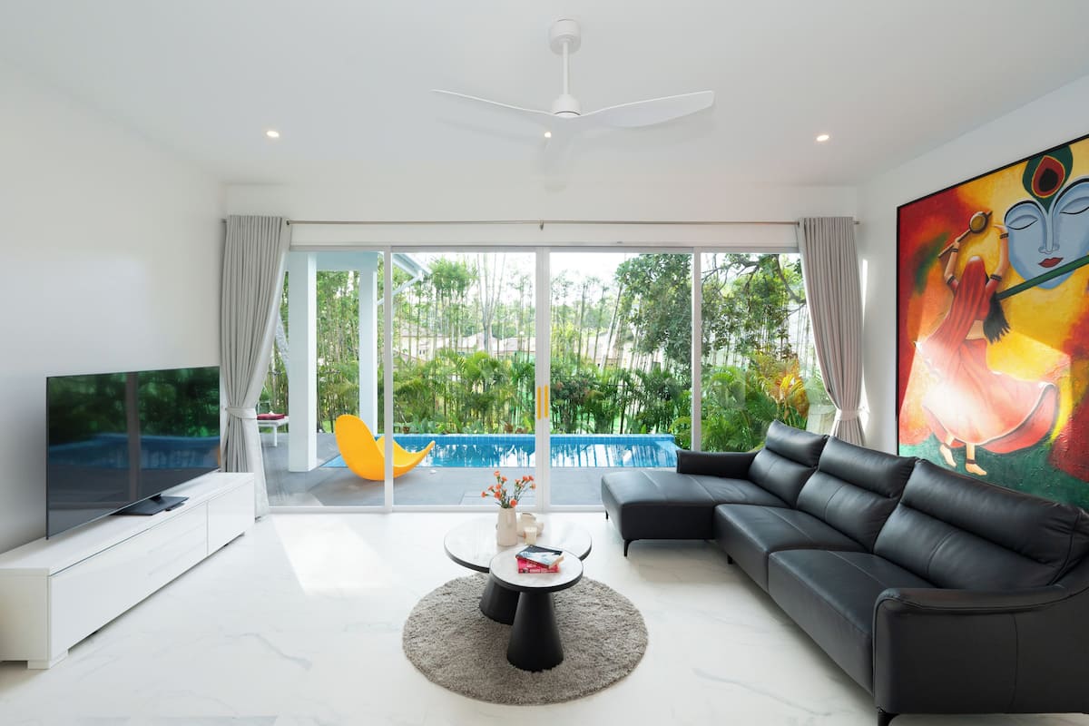 A modern living room with a sectional sofa, a flat-screen TV, a coffee table, and a large painting.