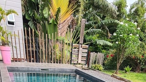 A clear swimming pool with metal handrails, surrounded by a garden with various plants and a wooden fence. - LEU ZARLOR Location Holiday residence 15 minutes from the beach, Double rooms (Saint-Leu)