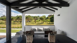 A modern outdoor seating area with a view of a grassy landscape and trees. - Villa Serenity - a paradise between golf and the sea (Foz do Arelho)