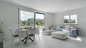 A spacious room with a dining area and a seating area. There are large windows providing natural light and views of the outdoors. - Villa Serenity - a paradise between golf and the sea (Foz do Arelho)