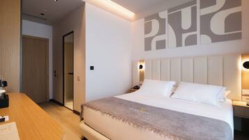 Een moderne hotelkamer met een groot bed, een houten bureau en een kunstwerk aan de wand.
