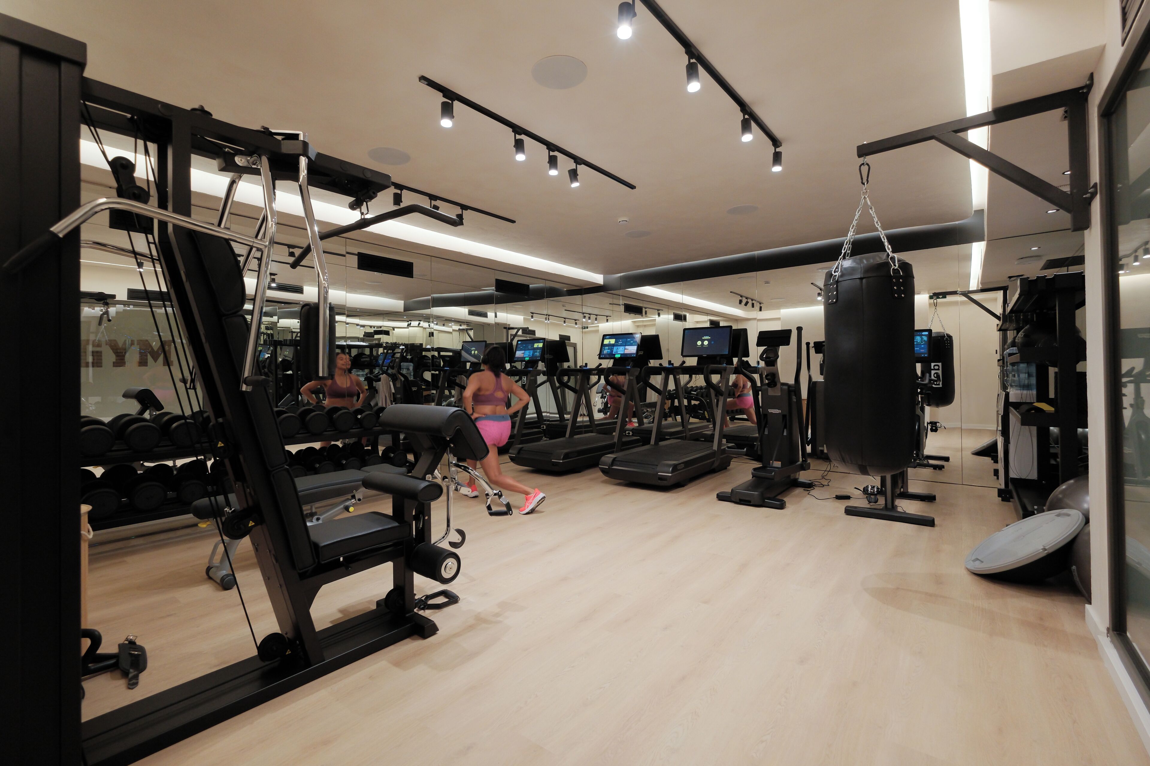 Een sportschool met trainingsapparatuur, loopbanden en een bokszak.