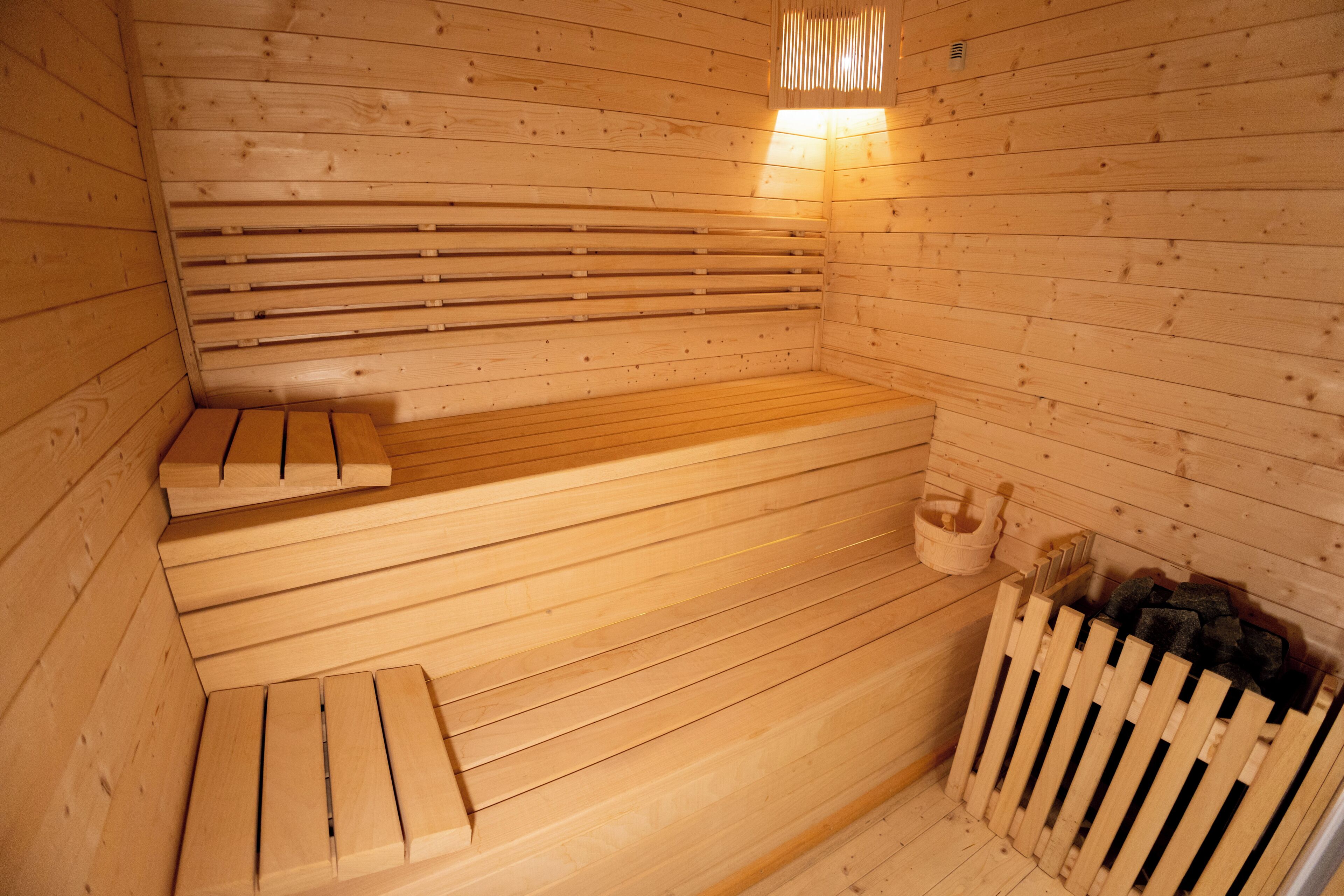 Una sauna de madera con bancos y un banco de madera al final.