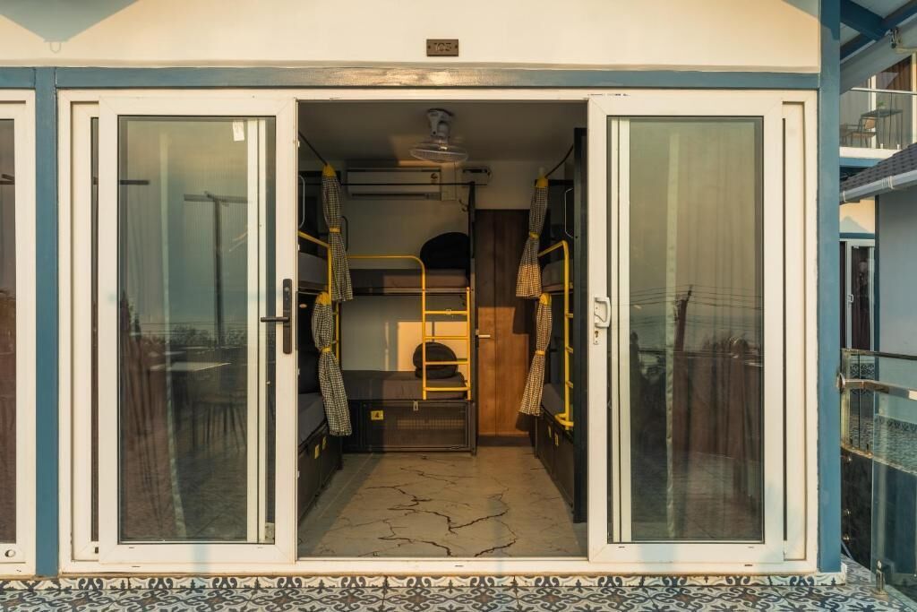 A narrow corridor with bunk beds, a small kitchenette, and a door leading to a balcony.