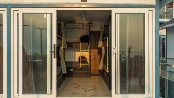 A narrow corridor with bunk beds, a small kitchenette, and a door leading to a balcony.