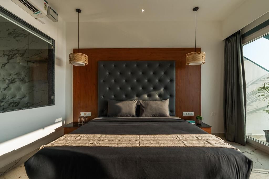 A modern bedroom with a large bed, a tufted headboard, two bedside tables, and a large window with curtains.