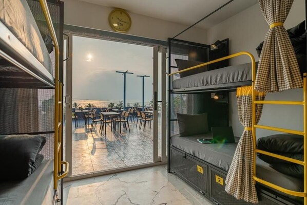 Habitación compacta con camas literas, puerta corredera a un patio exterior y un reloj a la vista.