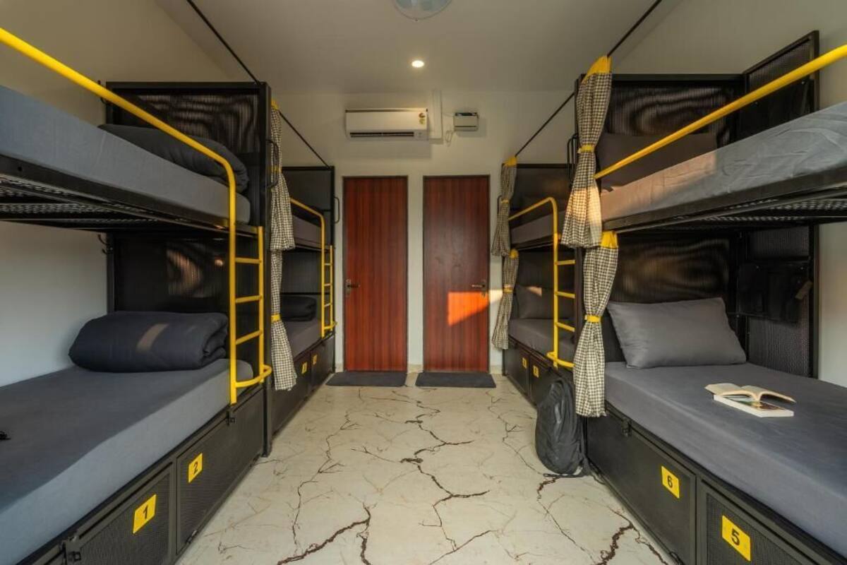 A dorm-style room with bunk beds, a wooden door, and a white floor with cracks.