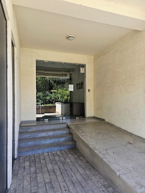 A concrete staircase leading to a glass door with a view of greenery outside.