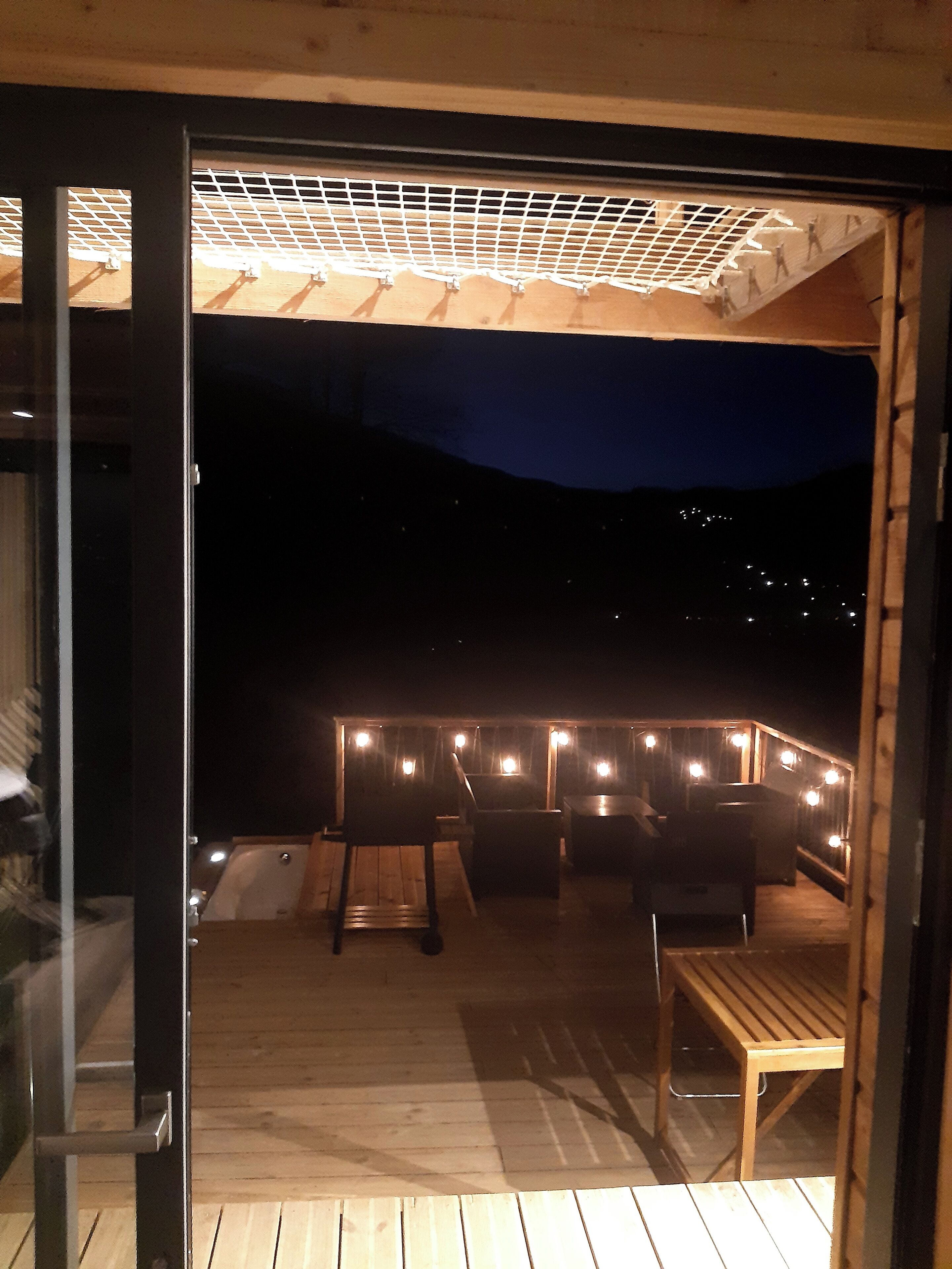 Une terrasse extérieure avec des meubles en bois et des guirlandes lumineuses.
