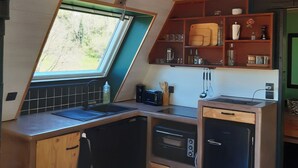 Een compacte keuken met een schuine kap, een raam en ingebouwde houten planken.