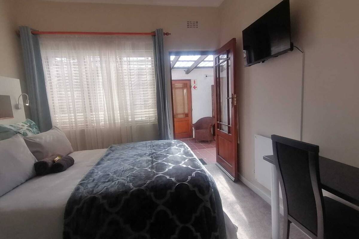A hotel room with a bed, a TV mounted on the wall, and a door leading to another room.