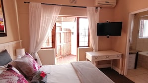 A bedroom with a bed, a desk, a TV, and an air conditioning unit. - Beulah Lodge (Cape Town)