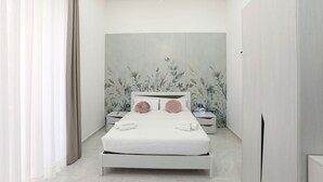A modern bedroom with a large bed, bedside tables, a wall-mounted light fixture, and a floral wallpaper design. - VivimiHome - CharmiNapoli Chiaia Room (Naples)