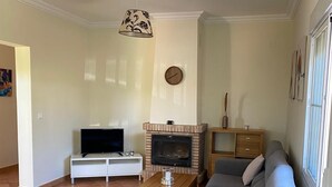 A modern living room with a sectional sofa, a flat-screen TV, a fireplace, and a dining area. - Chalet Villa Antonia (Ayamonte)
