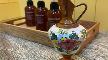 A marble countertop with a decorative ceramic pitcher and three bottles of body soap in the background.