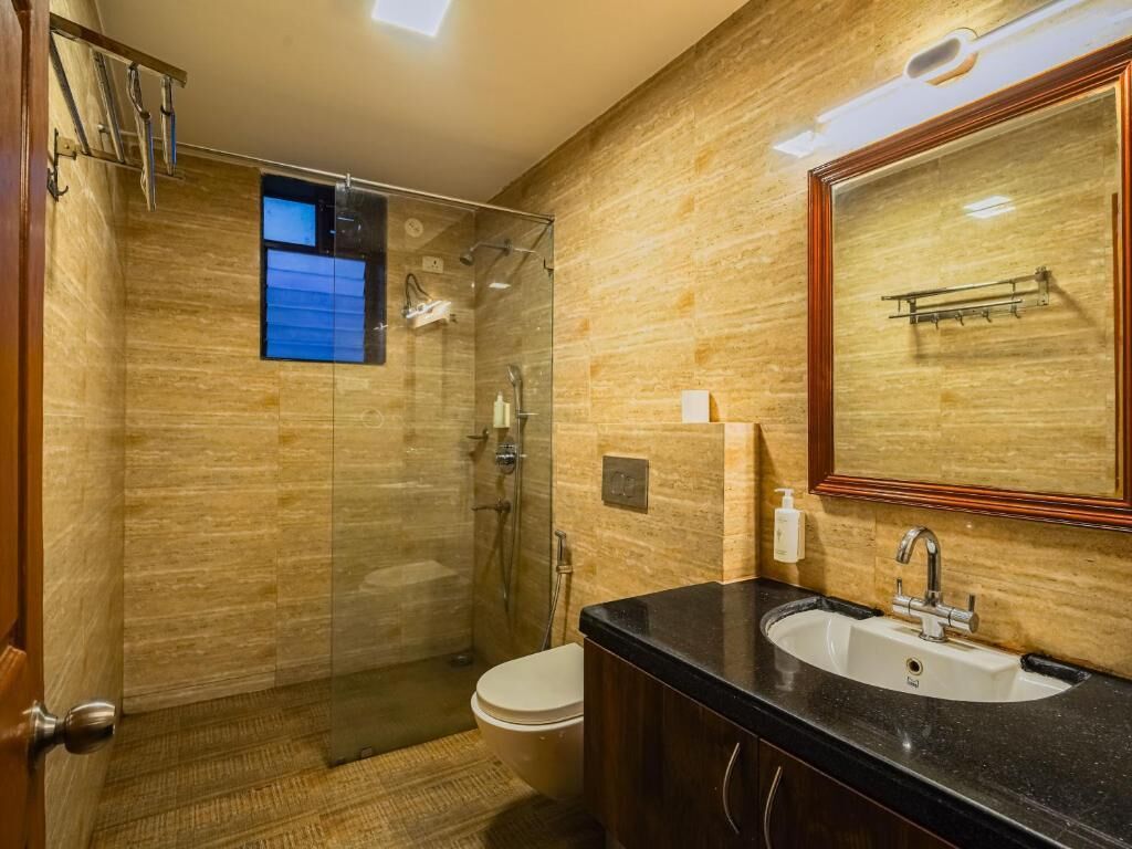 Ein modernes Badezimmer mit einer Duschkabine, einer Toilette und einem Waschbecken mit Spiegel.