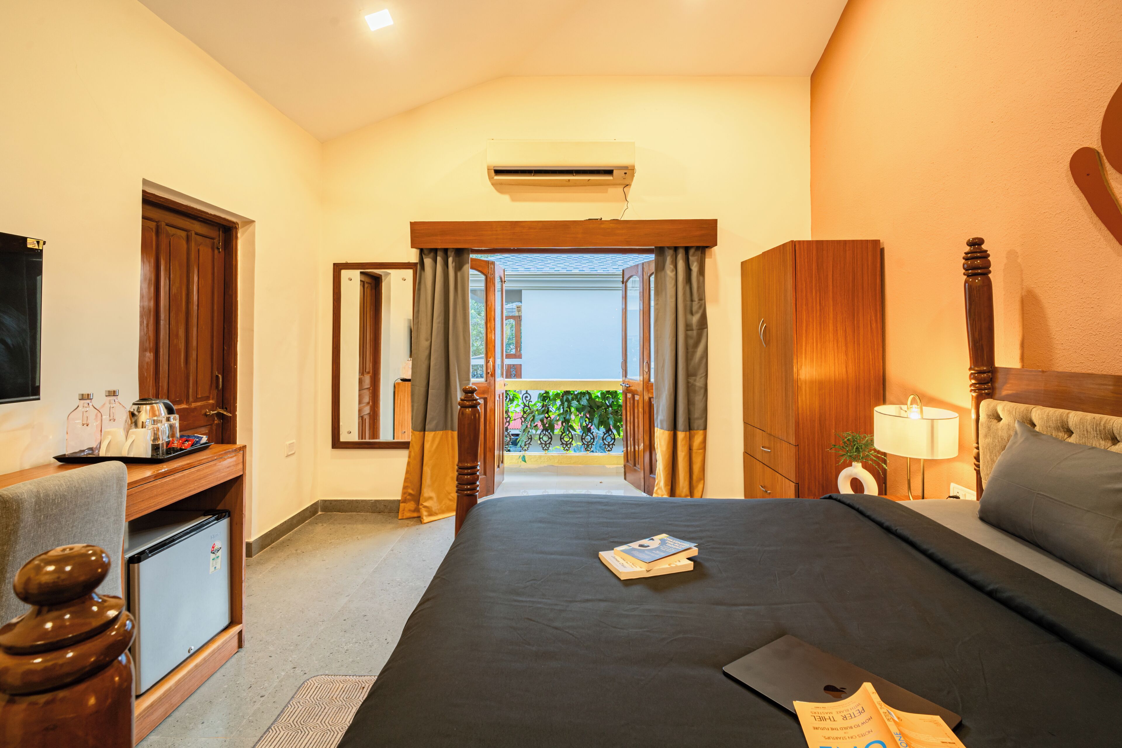 A hotel room with a bed, a desk, a refrigerator, and a view of the outside.