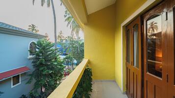A yellow exterior wall with a wooden door and a balcony with plants.