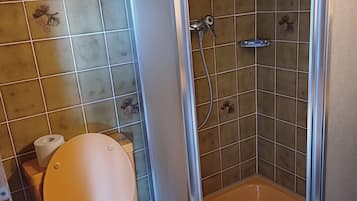 A bathroom with a toilet, a shower, and a tiled floor.
