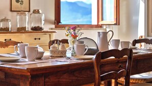 A wooden dining table with white ceramic dishes, a pitcher, and a vase with flowers. - La casa di Mia - country house (Torri del Benaco)