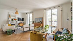 A modern living room with a glass dining table, white sofas, and a fireplace. - The Spirit Lifter, by Veeve (Paris)