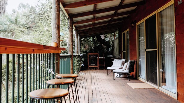 Une terrasse en bois avec des sièges d’extérieur, un espace couvert et de grandes portes-fenêtres coulissantes.