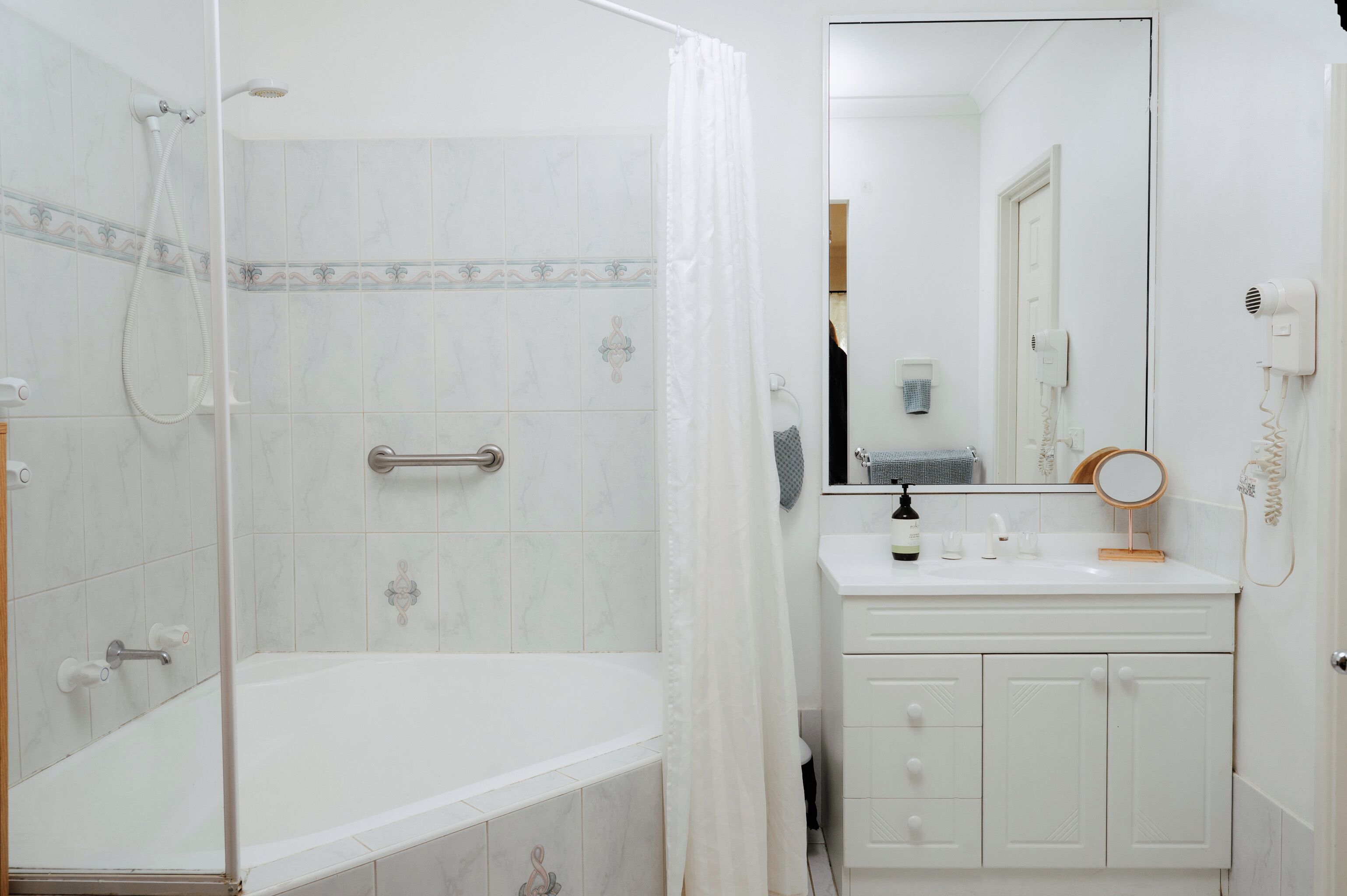 Ein Badezimmer mit Dusche, Badewanne, Waschtisch mit Spiegel und Handtuchhalter.