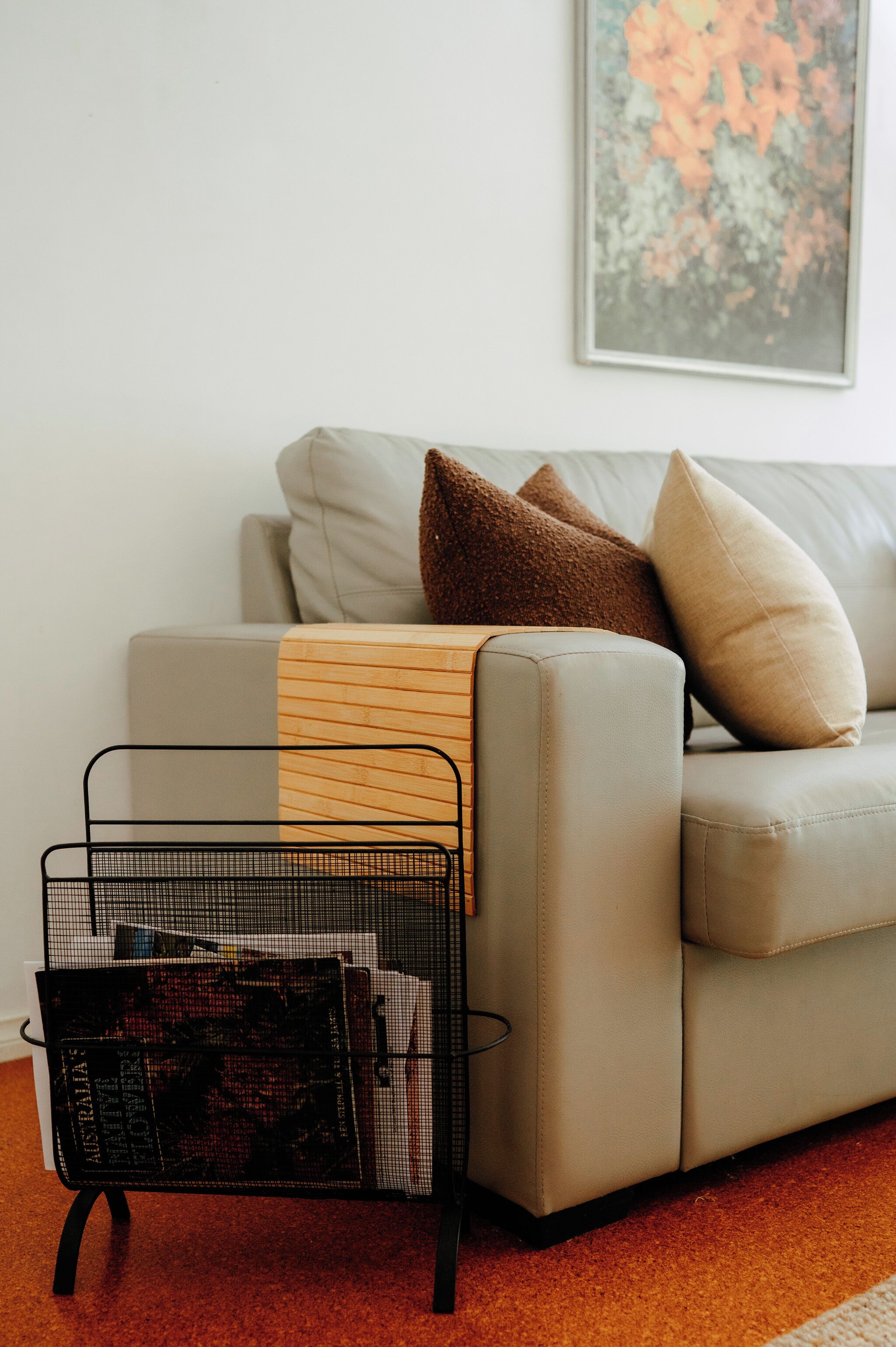 A living room with a sofa, a throw blanket, a wire basket, and a framed picture on the wall.