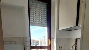 A compact kitchen with a gas stove, a sink, and a window with blinds.