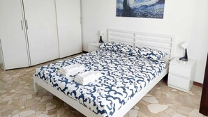 A bedroom with a bed, nightstands, a wardrobe, and a painting on the wall.