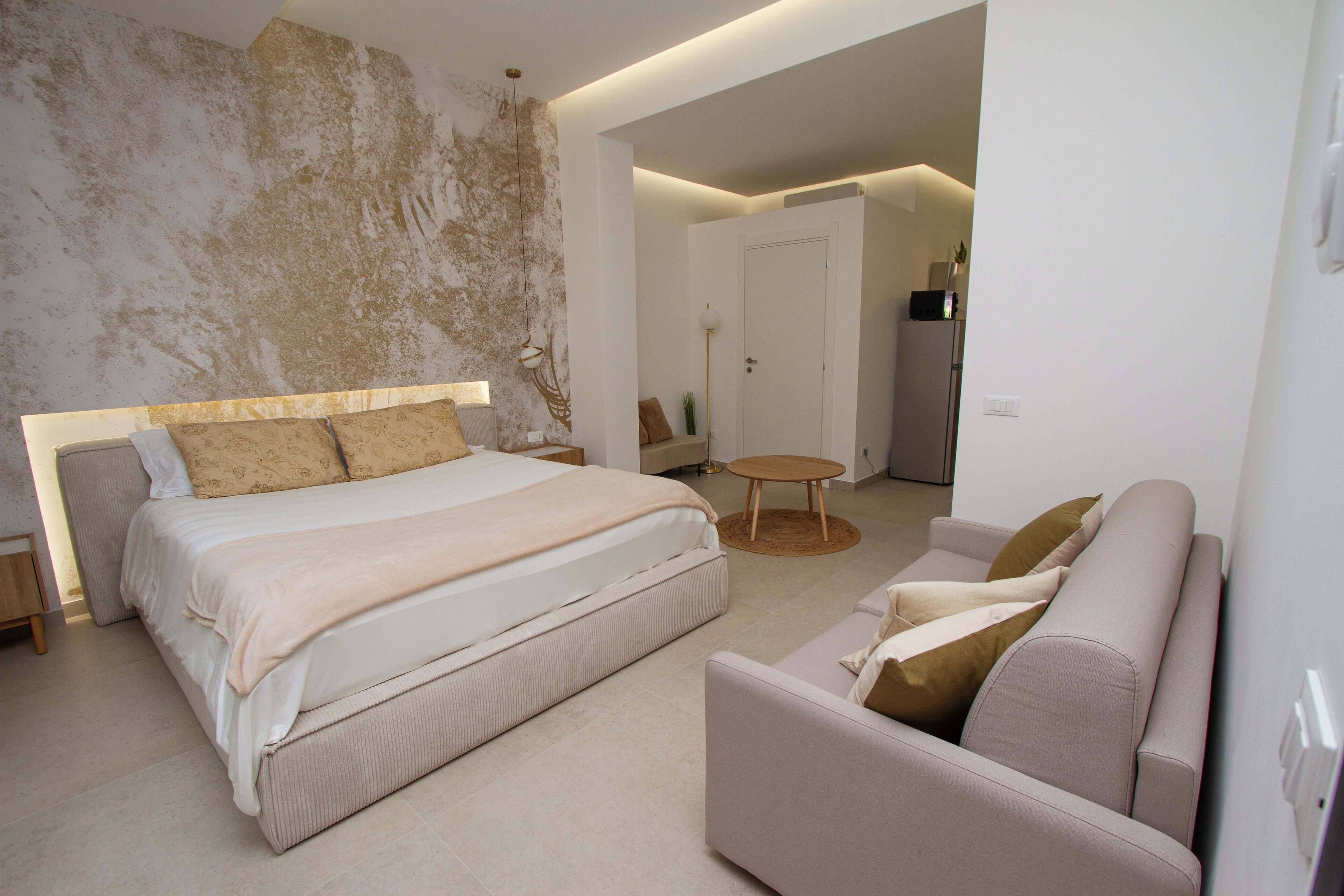 A modern bedroom with a large bed, a sofa, and a small round table.
