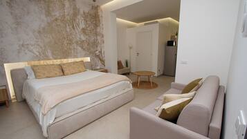 A modern bedroom with a large bed, a sofa, and a small round table.