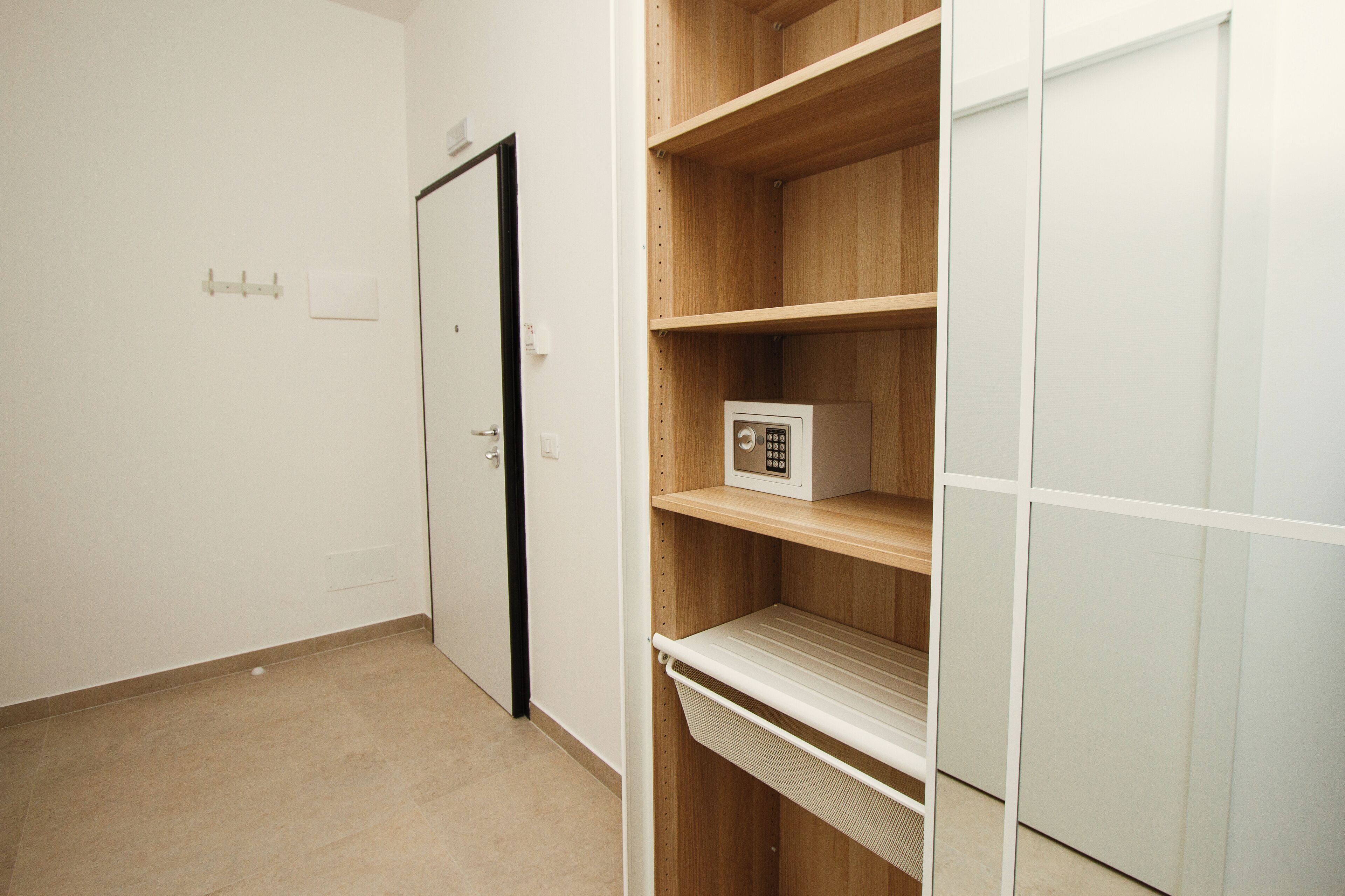 Una habitación con un armario de madera, una puerta blanca y un estante con un pequeño dispositivo electrónico.