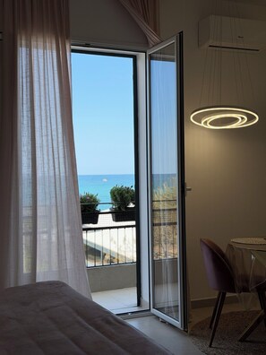A bedroom with a large sliding glass door leading to a balcony with a view of the sea. - Suites Domus Fysi (Palermo)