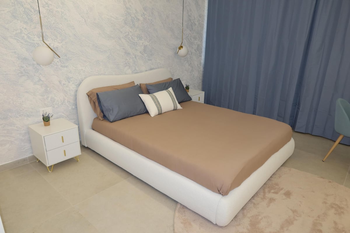 A bedroom with a bed, nightstands, a small table, and a chair.
