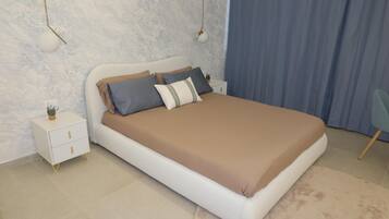 Ein Schlafzimmer mit einem Bett, Nachttischen, einem kleinen Tisch und einem Sessel.