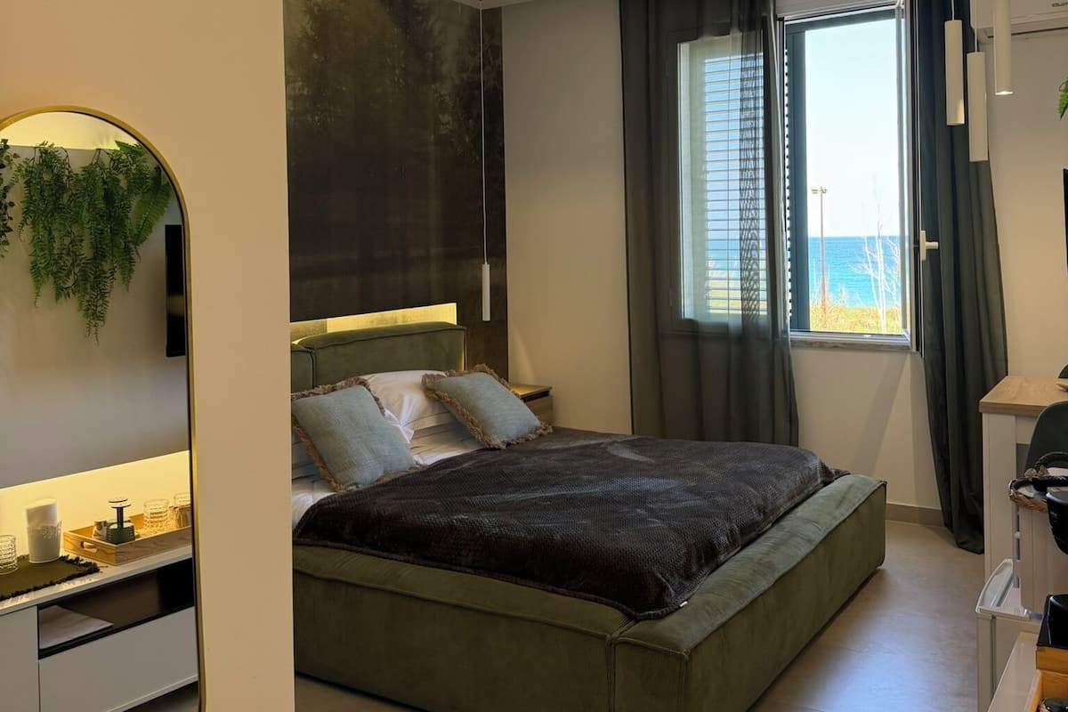 A modern bedroom with a bed, bedside table, and a large window.