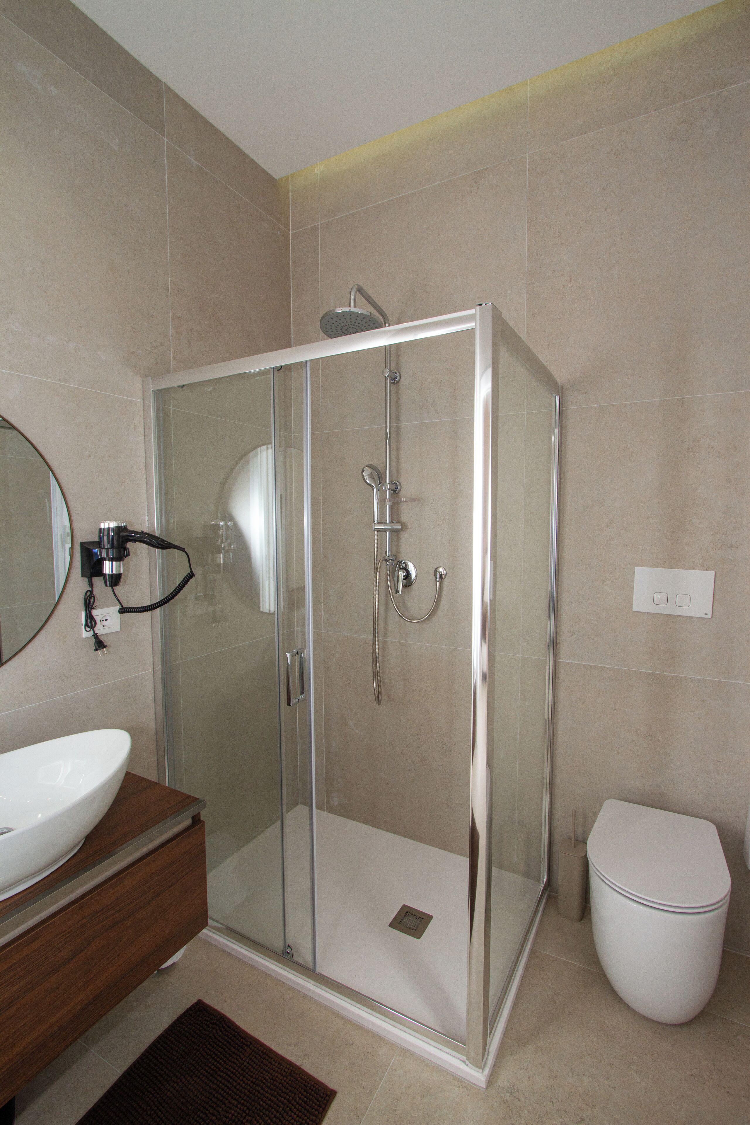 A modern bathroom with a glass-enclosed shower, a white sink, and a toilet.