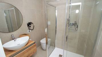 A modern bathroom with a glass-enclosed shower, a white sink, and a wooden vanity.