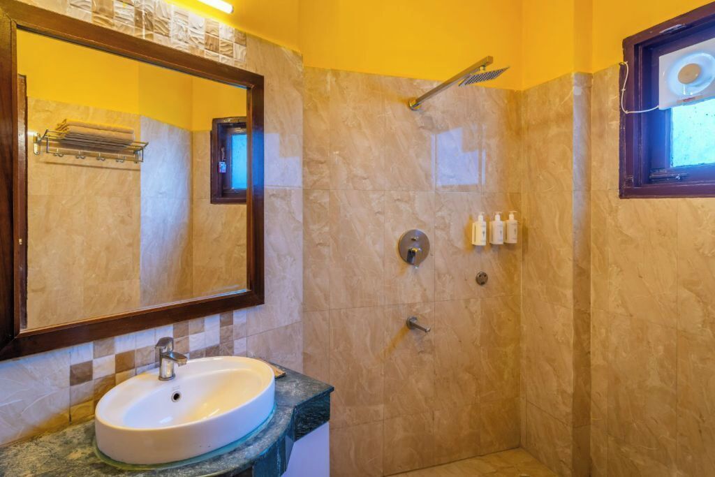 Un baño con lavamanos, espejo, ducha y artículos de aseo.