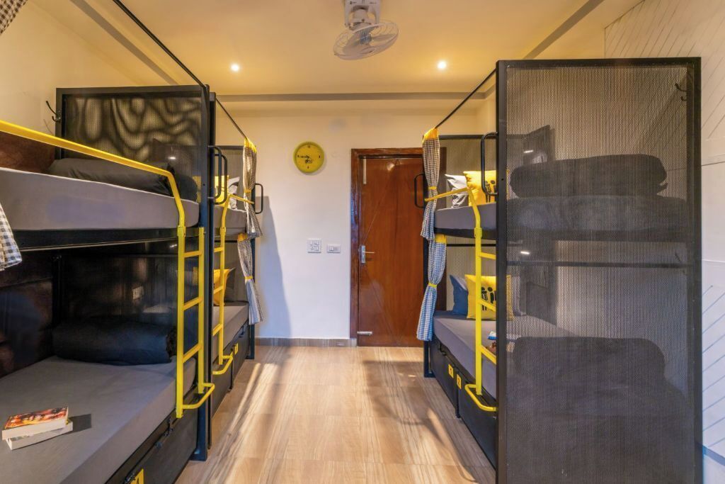 Une pièce avec des lits superposés, une horloge au mur et une porte.