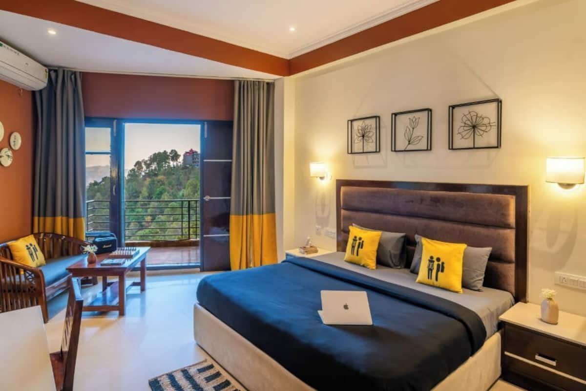 Une chambre d’hôtel avec un grand lit, un bureau et un balcon doté de rideaux.