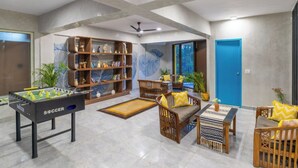 A spacious living area with a foosball table, wooden furniture, and a bookshelf. - The Hosteller Kasauli (Kasauli)