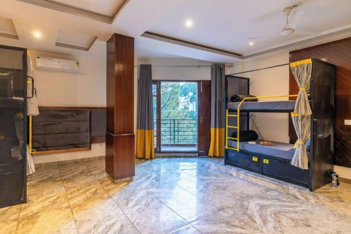 Une chambre d’hôtel avec un lit superposé, un canapé, un réfrigérateur et une vue sur l’extérieur.