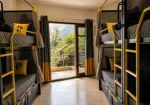 A dormitory room with bunk beds, a sliding glass door to a balcony, and curtains. - The Hosteller Kasauli (Kasauli)